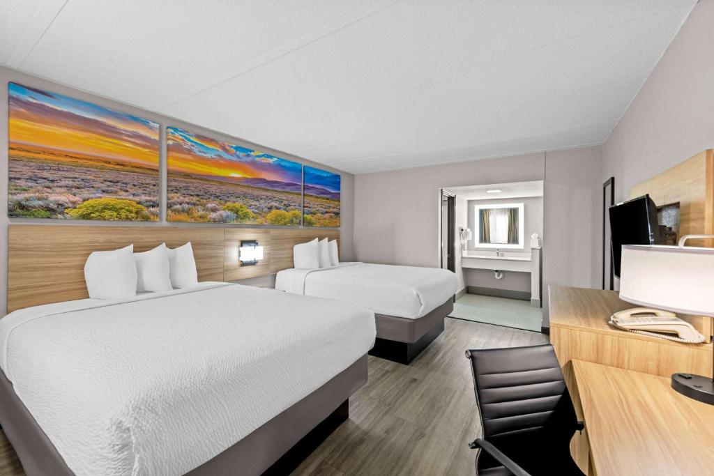 a hotel room with two beds and a desk at Days Inn by Wyndham Gainesville in Gainesville