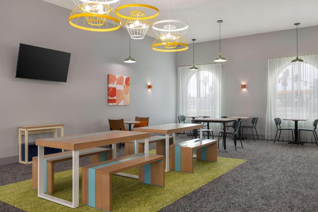 a room with tables and chairs and a flat screen tv at Spark By Hilton Santa Nella in Santa Nella