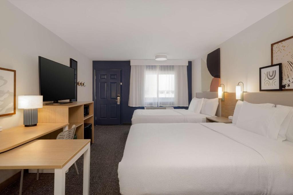 a hotel room with two beds and a flat screen tv at Spark By Hilton Santa Nella in Santa Nella