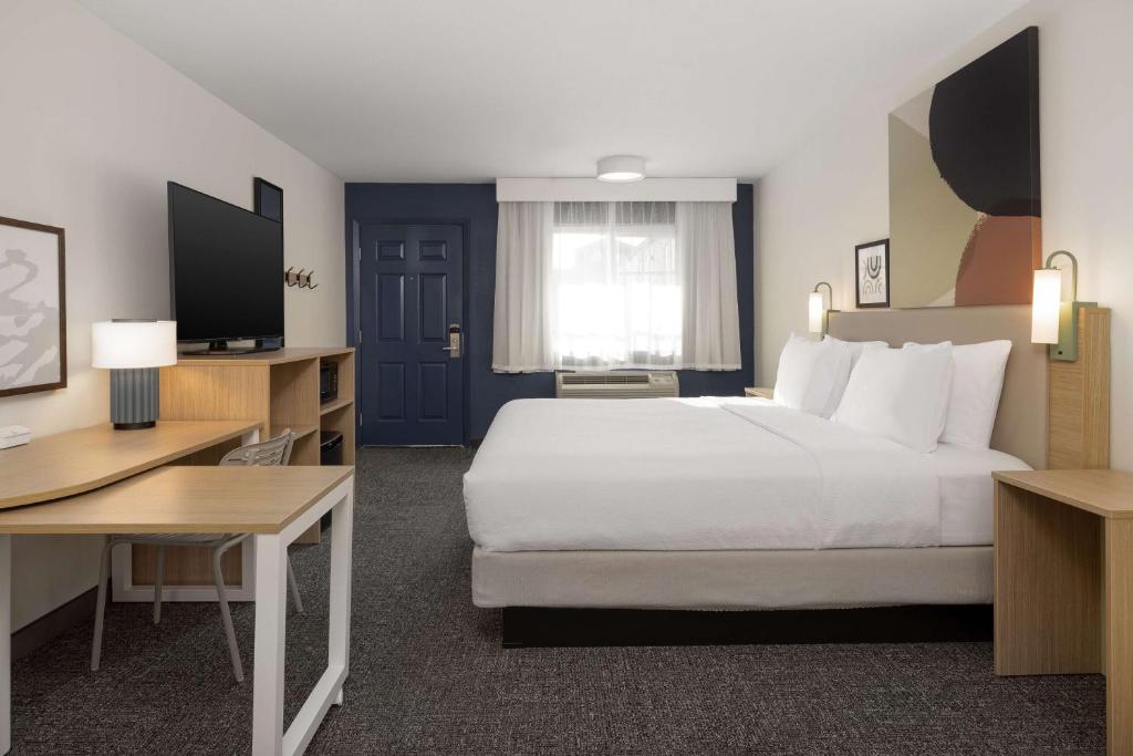 a hotel room with a large bed and a desk at Spark By Hilton Santa Nella in Santa Nella