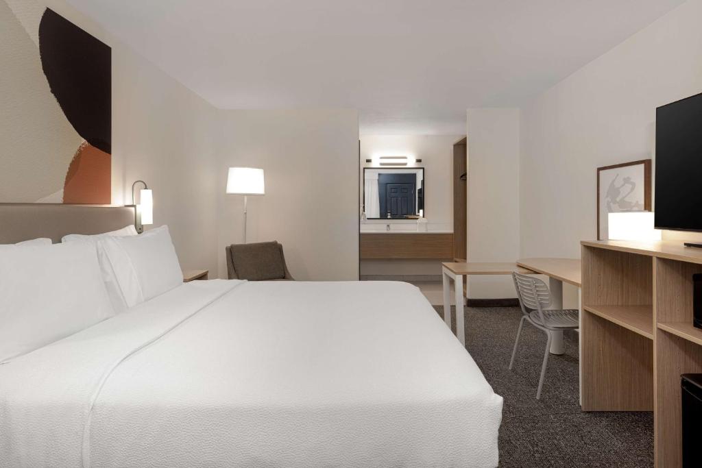 a hotel room with a large white bed and a desk at Spark By Hilton Santa Nella in Santa Nella