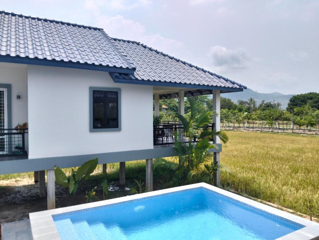 a villa with a swimming pool in front of a house at Baksaei Retreat Ricefield Villas in Kampot