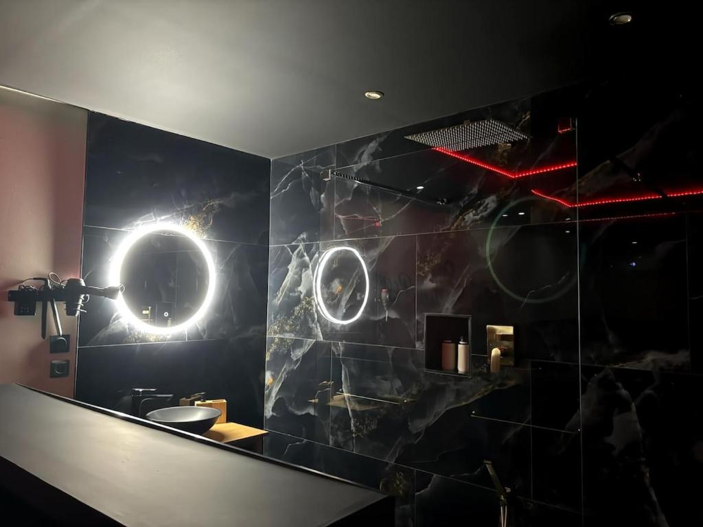 a bathroom with a black wall with lights on it at Romantique room,balnéo,mirroir,parking in Grenoble