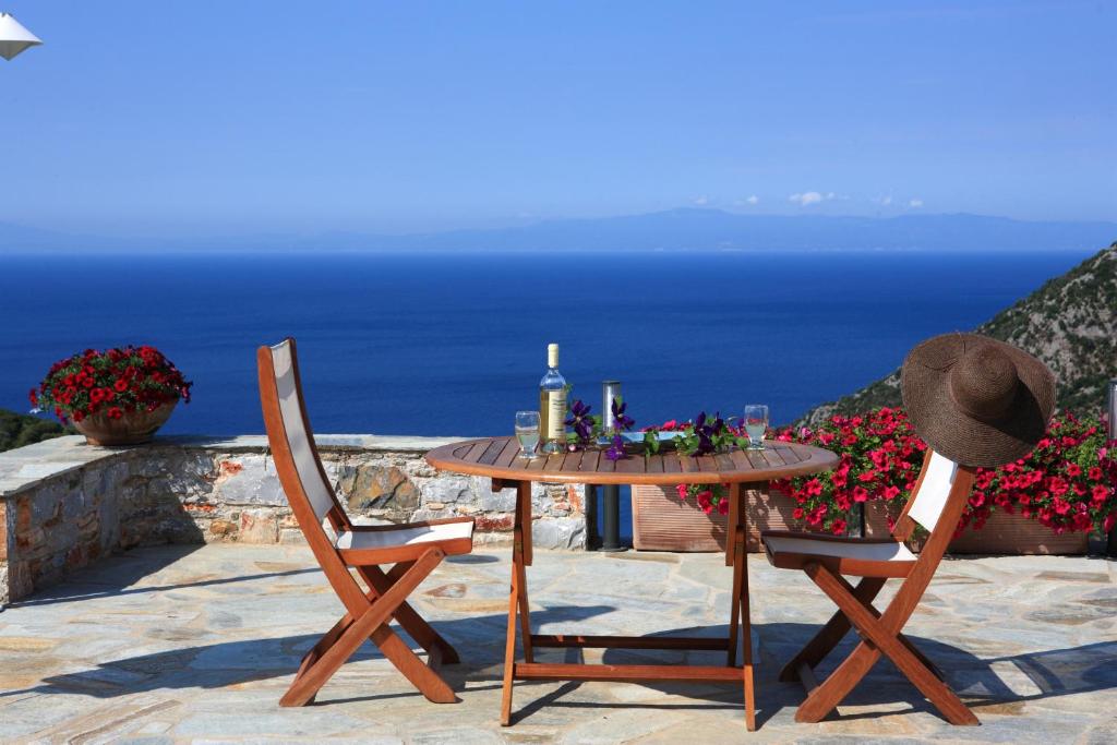 a table with a bottle of wine and two chairs at Elies Houses in Agnontas
