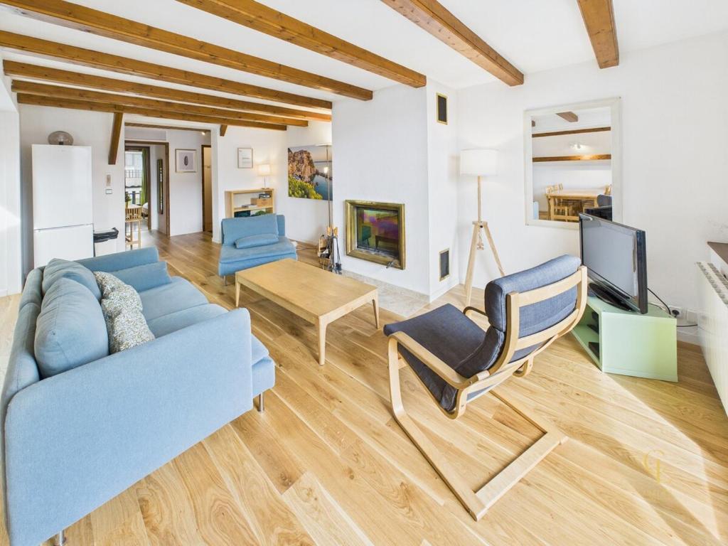 un salon avec un canapé bleu et une télévision dans l'établissement Appartement Terrasse, vue sur les montagnes et Parking, à Bussang