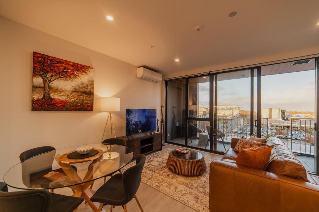 Una sala de estar con un sofá y una mesa de cristal. en Central 1BR Apt - Balcony Kitchen & Bath, en Christchurch