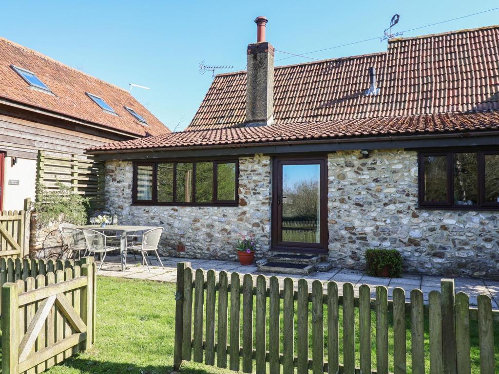 une maison en pierre avec une clôture en bois devant elle dans l'établissement Weathervane Cottage, à Monkton