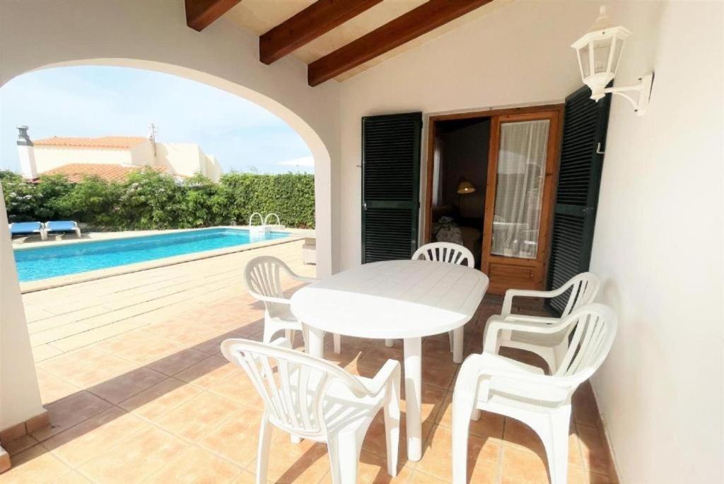 a white table and chairs on a patio with a pool at Villa Mar in Cala en Bosc