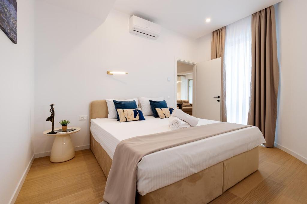 ブカレストにあるCentral Suitesの白いベッドルーム(青い枕の大型ベッド付)