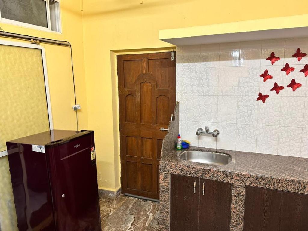 a kitchen with a sink and a wooden door at James Guesthouse in Bogmalo