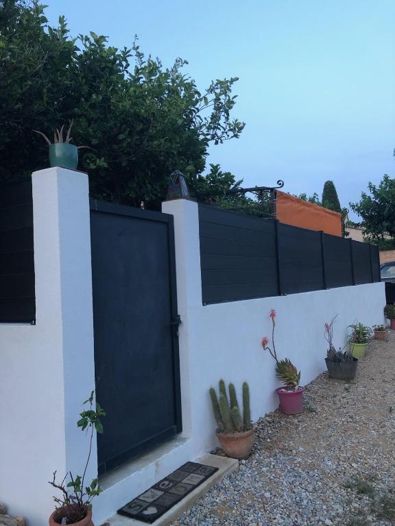 un mur blanc avec une porte noire et des plantes en pot dans l'établissement la roseraie, à Six-Fours-les-Plages