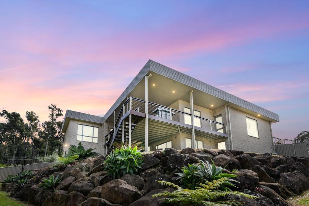 a house on a hill with rocks at Serene Luxury Retreat on Malua Bay in Malua Bay