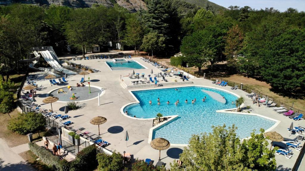 an overhead view of a large swimming pool with people in it at Camping La Grand'Terre 4 étoiles - Linge de maison inclus - Clim - TV - Plancha - Lave-vaisselle - 4 personnes 2 chambres in Ruoms