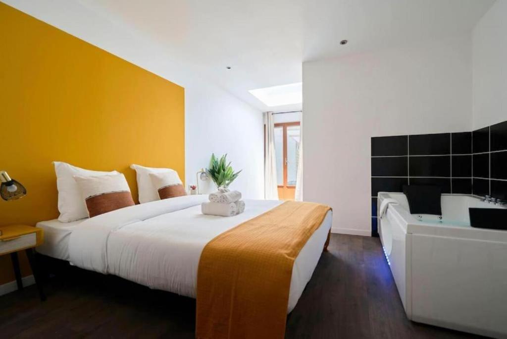 Un dormitorio con una cama grande y una bañera. en NG Prestige - Suite Soleil Doré - Balnéo - Cuisine - Jardin, en Roubaix