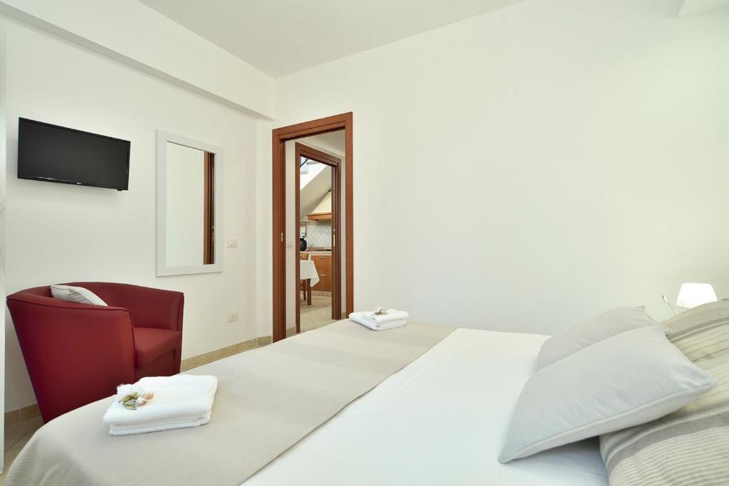 - une chambre blanche avec un lit et une chaise rouge dans l'établissement Villa del Colle con piscina privata, à Ispica