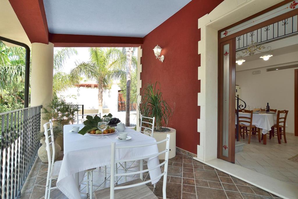une salle à manger avec une table blanche sur un balcon dans l'établissement Villa del Colle con piscina privata, à Ispica