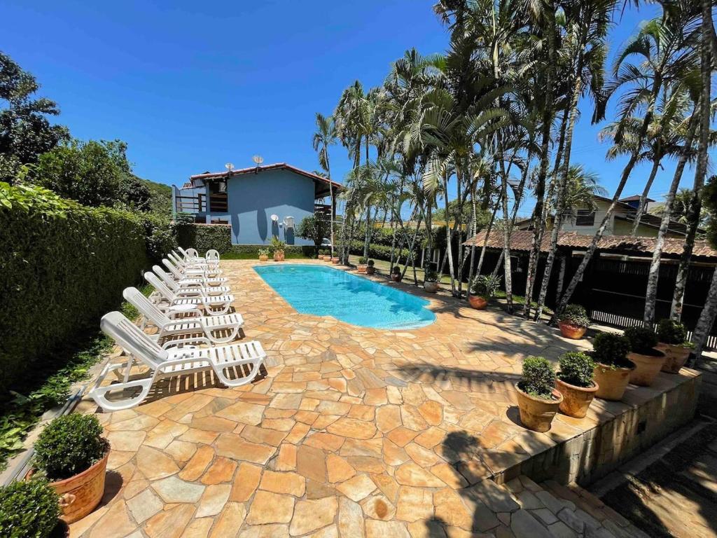 a group of lounge chairs and a swimming pool at Casa de Condomínio em Maresias próximo a praia! in São Sebastião