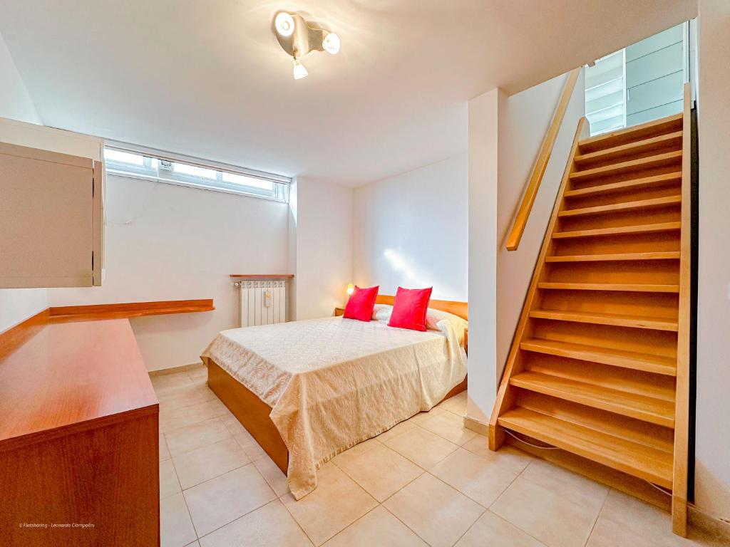 una camera da letto con un letto con cuscini rossi e una scala di Brunacci BEleven Suite - 5 min dai Navigli a Milano