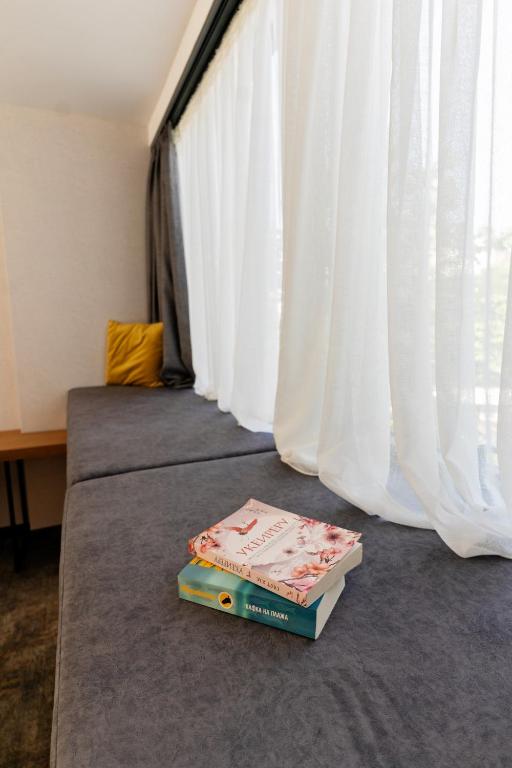 two books sitting on a bed next to a window at MM Boutique Hotel in Burgas