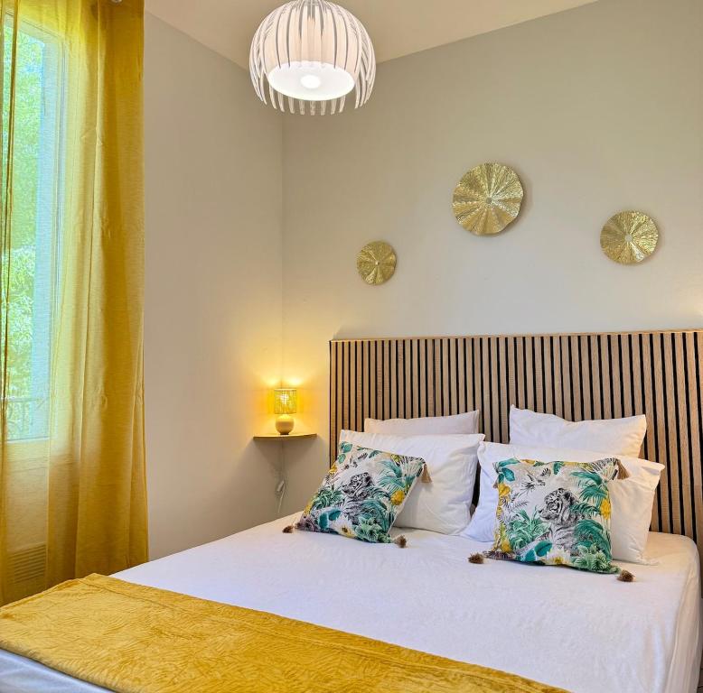 une chambre avec un lit avec des draps blancs et des oreillers dans l'établissement Soleil Arlésien, à Arles