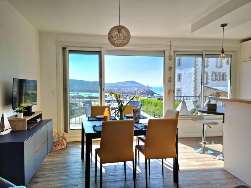 - un salon avec une table, des chaises et une grande fenêtre dans l'établissement Résidence trozoul Le Goëland qui chante, à Trébeurden