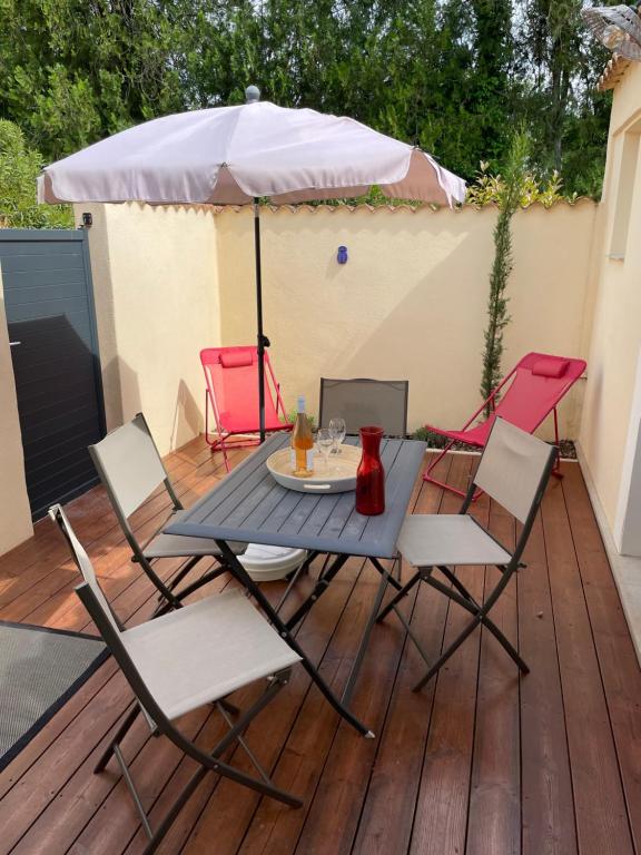 une table et des chaises sur une terrasse avec un parasol dans l'établissement Bastidon et son patio à Saint Rémy de Provence, à Saint-Rémy-de-Provence