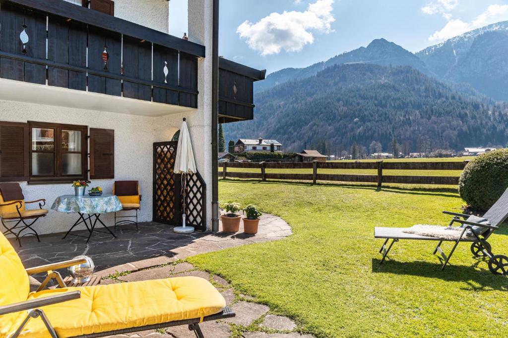 a patio with a table and chairs on a lawn at Ferienhaus Frühholz - Fewo Alpspitz in Grainau