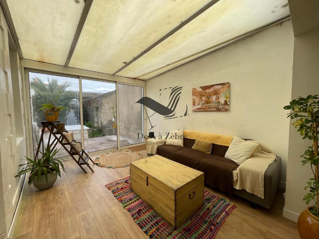 a living room with a couch and a large window at Cocon Bleu - Maison idéalement située avec jardin in Rochefort