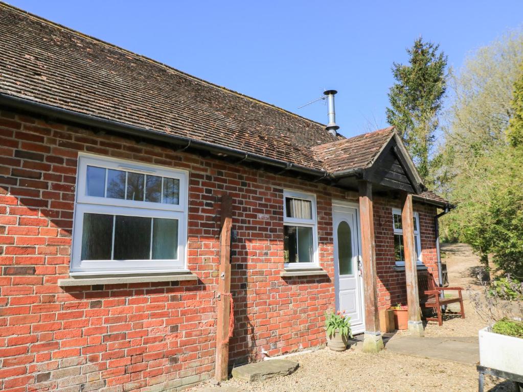 a red brick house with a white door at Grist Mill Cottage in Fontmell Magna