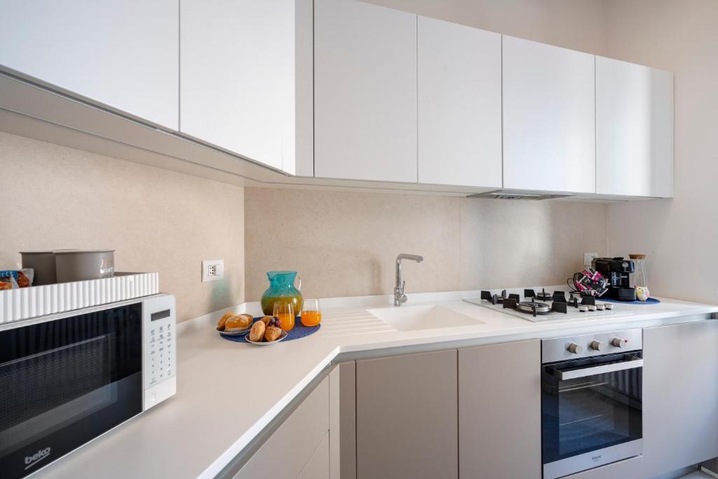 a kitchen with white cabinets and a plate of fruit on the counter at Martini Matera 2-luxury apartment in Matera