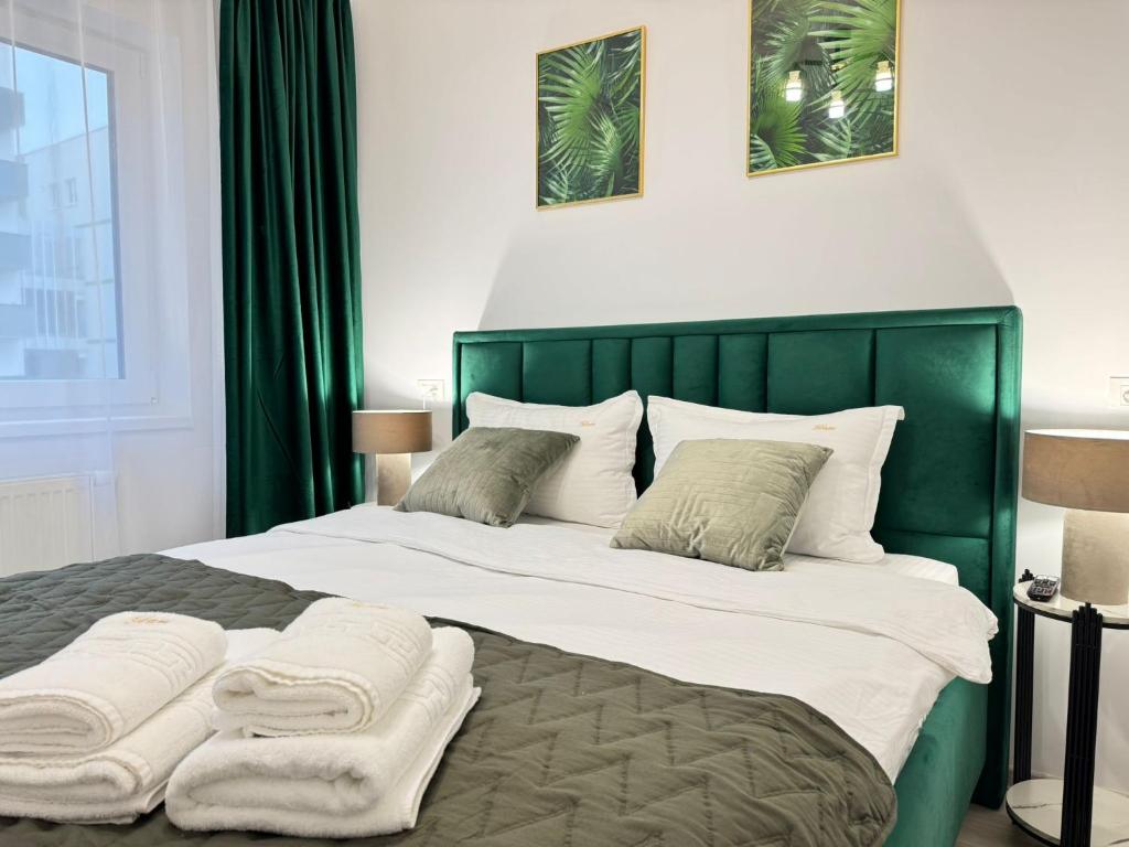 a bedroom with a large bed with a green headboard at Coresi Area Luxury GAP Apartments in Braşov
