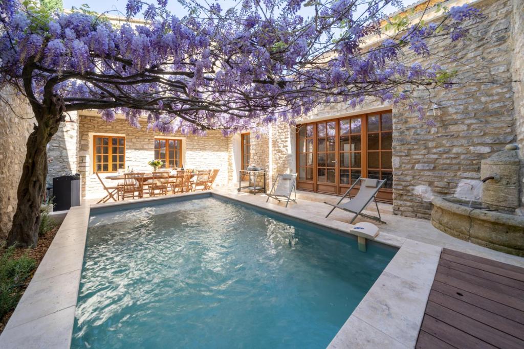 einen Pool im Garten mit einem Baum mit lila Blumen in der Unterkunft Exceptionnel - Couvent entièrement rénové - classé Patrimoine - Piscine, au calme et à 100 m du coeur de l'Isle in LʼIsle-sur-la-Sorgue