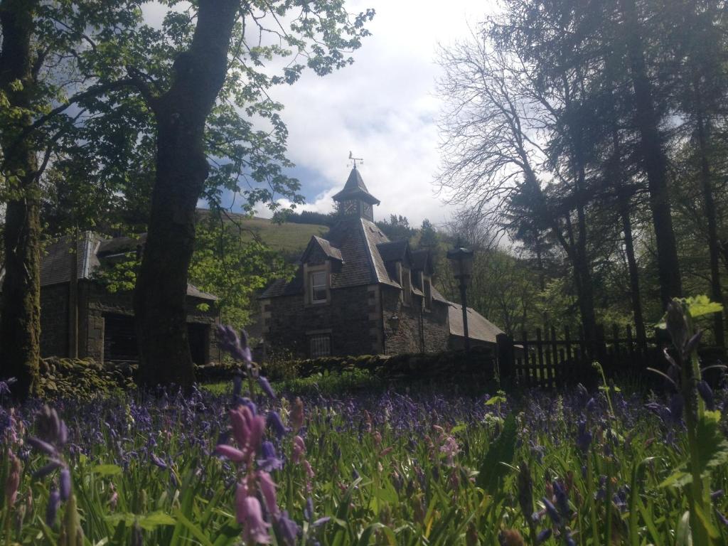 an old house in the middle of a field of flowers at Hearthstanes Steading in Polmood