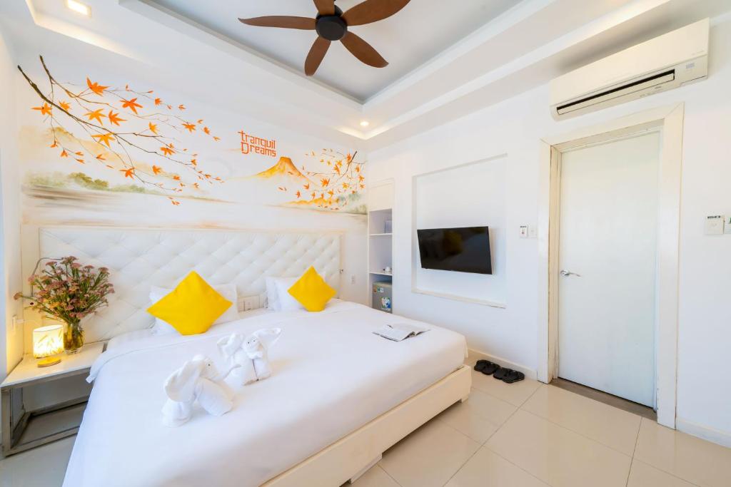 A bedroom with a decorated padded headboard, yellow pillows, air conditioning and television.