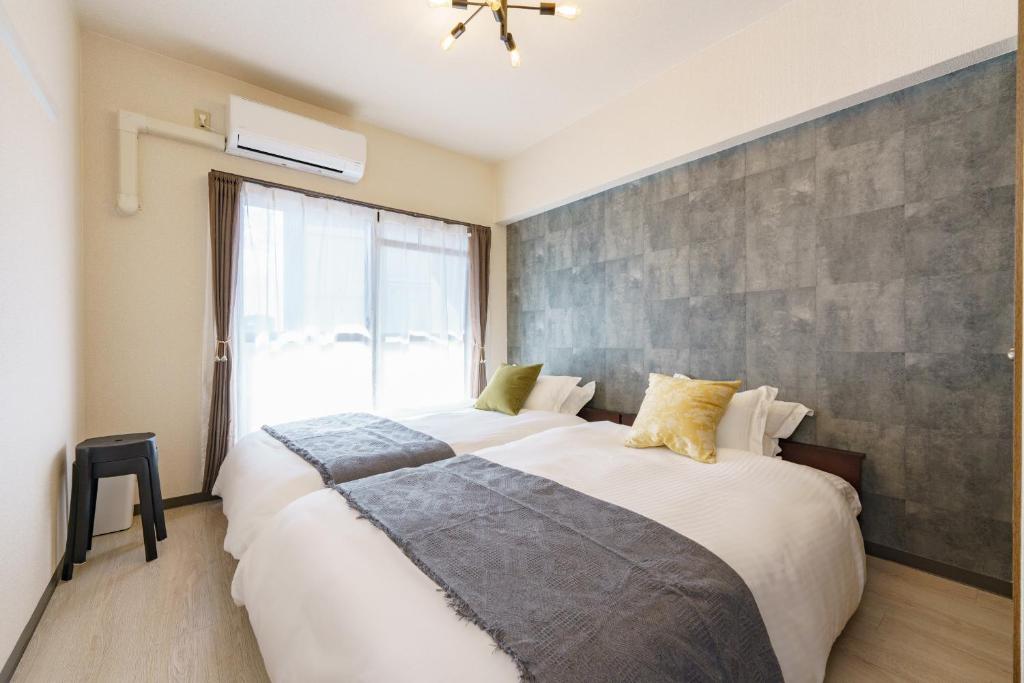 a bedroom with two beds and a large window at Central Nagoya Stays in Nagoya