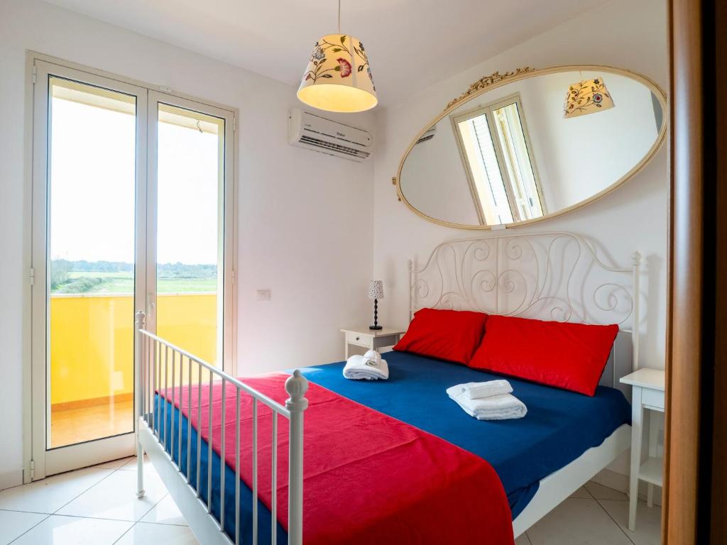 a bedroom with a bed with red and blue sheets and a mirror at Villa Mirò - Escape to Salento in Melendugno