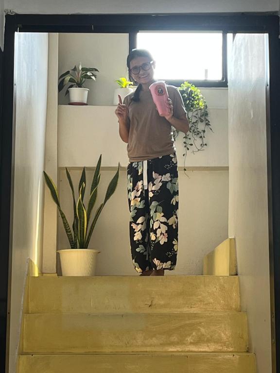 a woman standing on the stairs holding a pink cell phone at Lazy Gibbon 2 Chiang Mai - Haiya in Chiang Mai