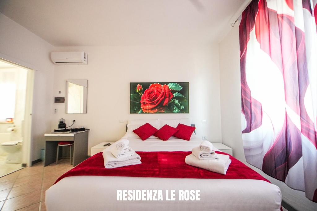 a bedroom with a large white bed with red pillows at Residenza Le Rose in Peschiera del Garda