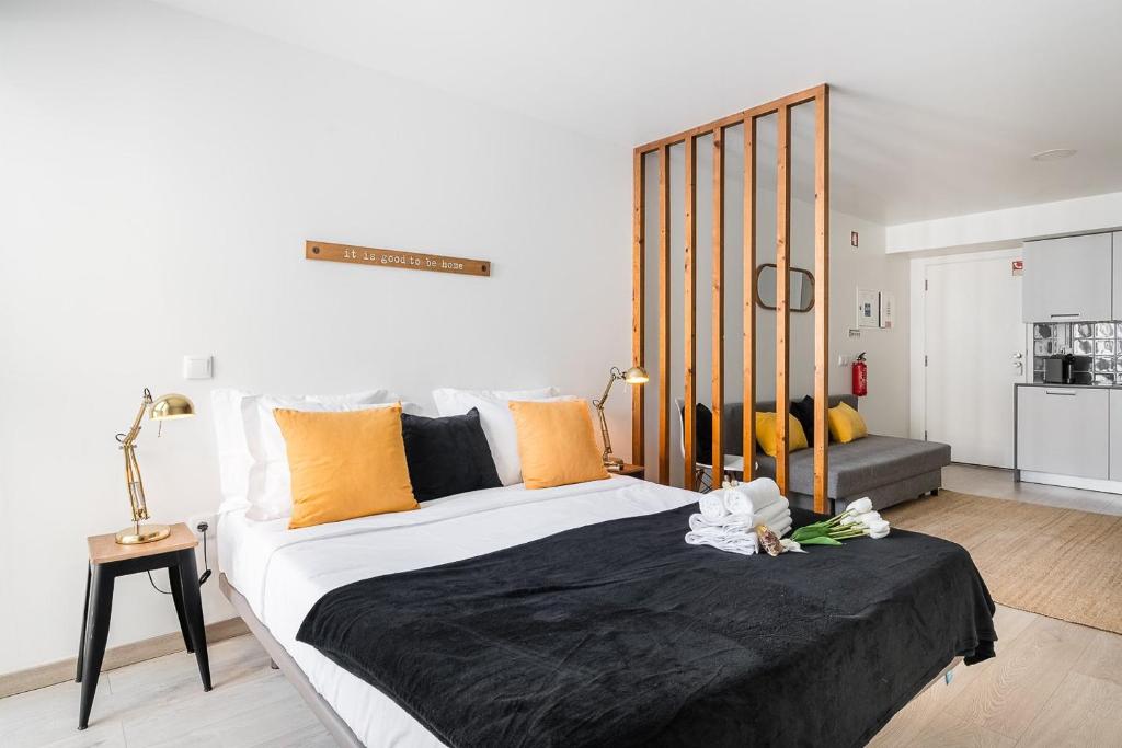 ein Schlafzimmer mit einem großen Bett mit orangefarbenen Kissen in der Unterkunft GuestReady - Ria Reflection Studios in Aveiro