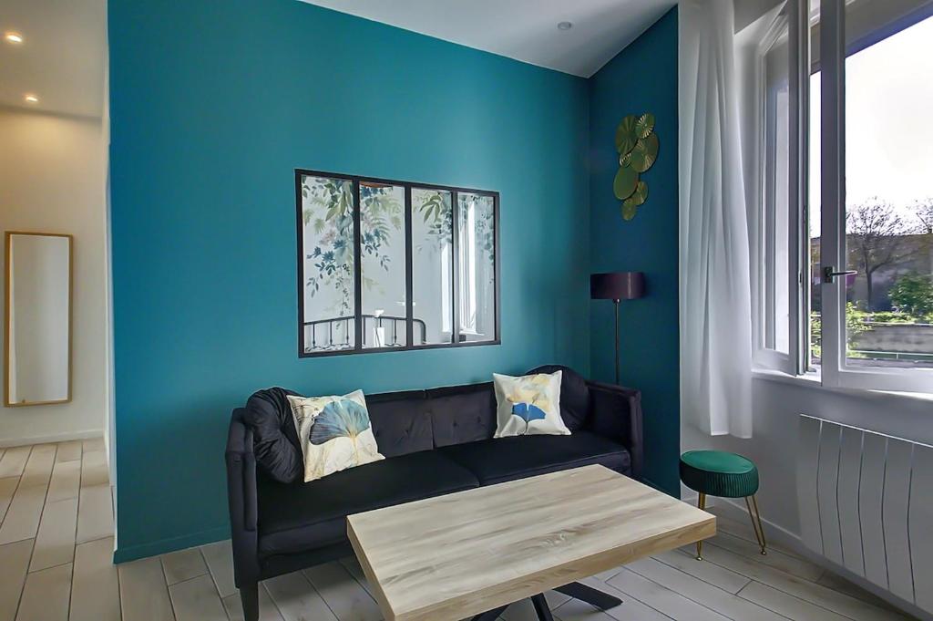 un salon avec un canapé et un mur bleu dans l'établissement Saint Genevieve Chic, à Lyon