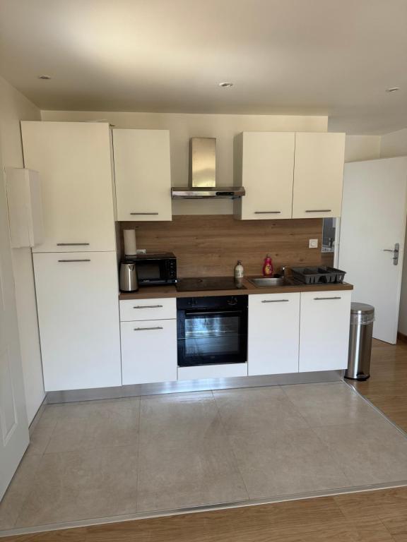 une cuisine avec des armoires blanches et un four à plaques de cuisson dans l'établissement T2 Rénové St-Priest centre avec Parking Privé, à Saint-Priest