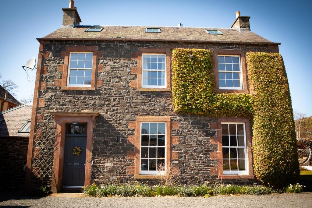 an ivy covered house with a blue door at Starbright Cottage in Peebles