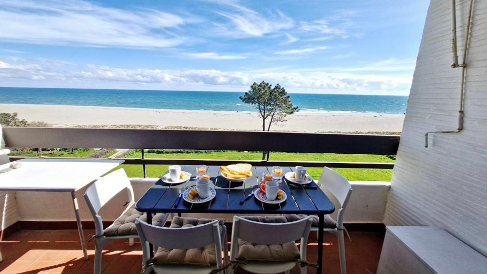 une table sur un balcon avec vue sur la plage dans l'établissement Paradis Bleu - Face à la mer - Wifi - parking, à Saint Cyprien Plage