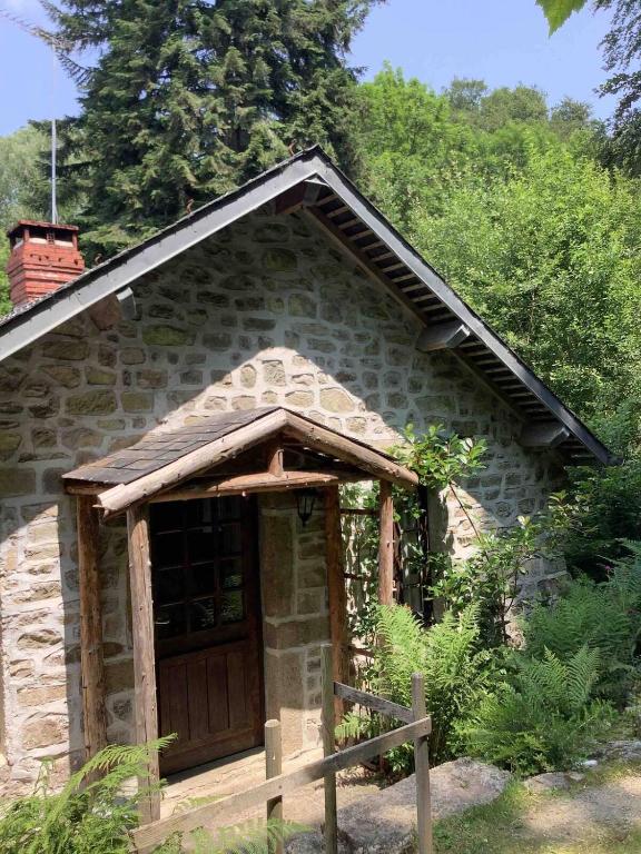 ein Steingebäude mit einer Holztür davor in der Unterkunft Woodland Cottage in Faux-la-Montagne