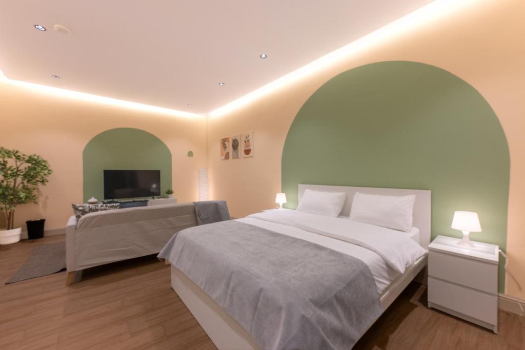 a bedroom with a large bed and a flat screen tv at بيتك - Baytak in Al Madinah