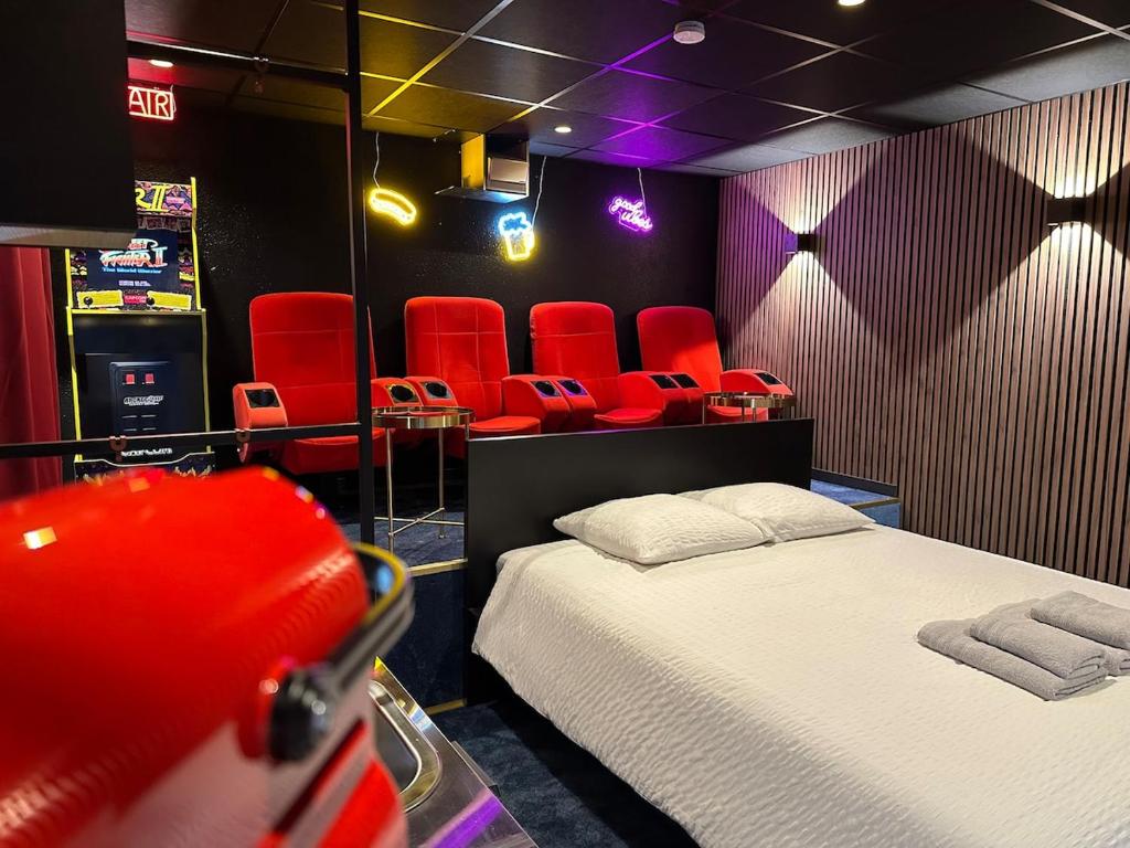 Cette chambre comprend un lit et des chaises rouges. dans l'établissement 4K cinema, Jacuzzi, à Mérignac
