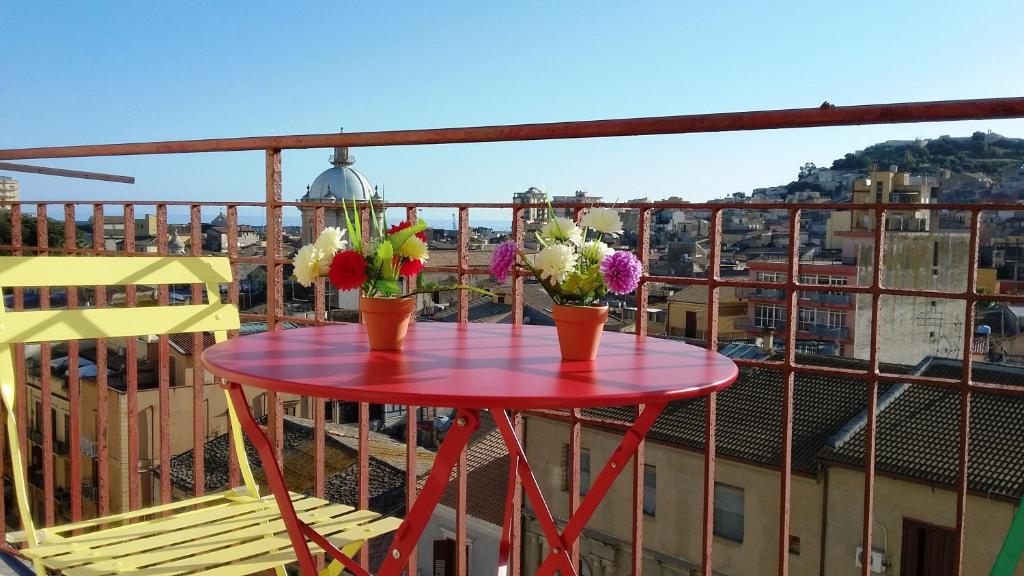 uma mesa vermelha com flores em cima de uma varanda em Castel Sant'Angelo sea view em Licata