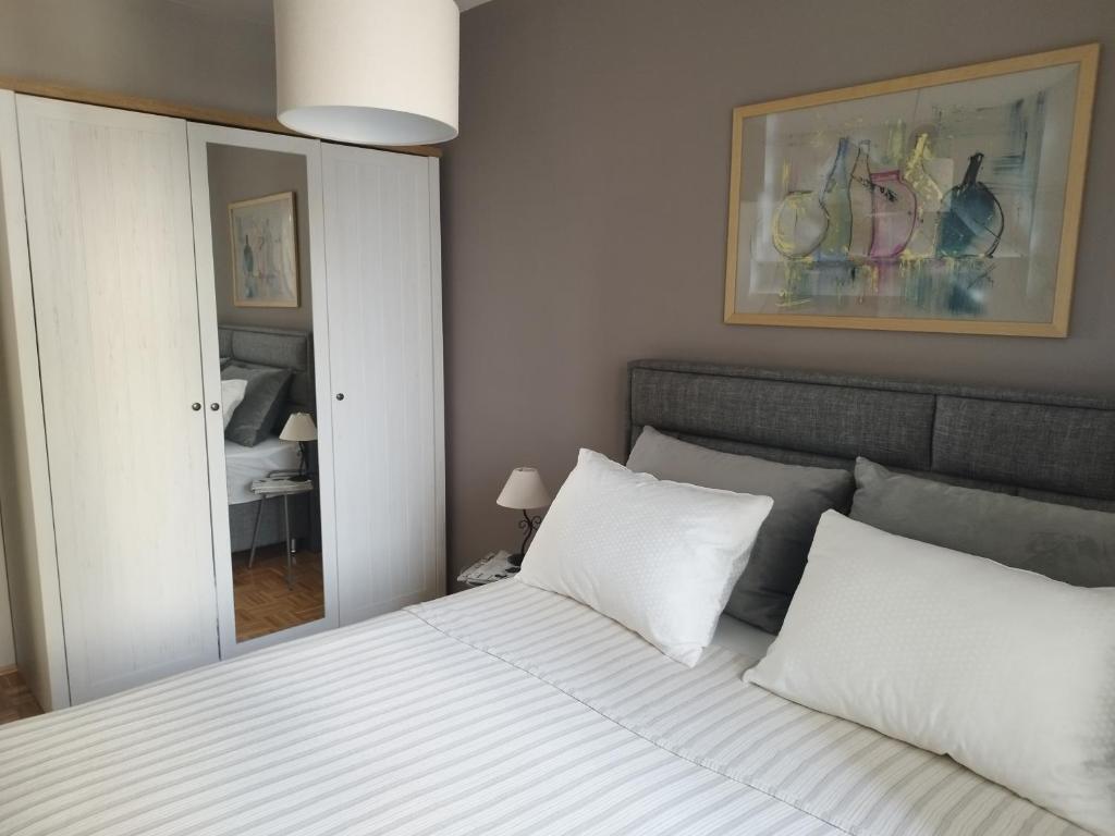 Un dormitorio con una cama con sábanas blancas y un espejo. en Royal Apartman, en Bijeljina