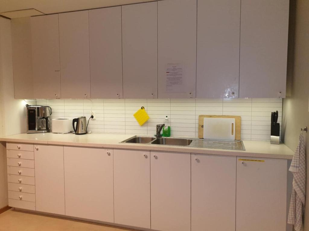 a kitchen with white cabinets and a sink at Koselig rom i sentrum Gratis Wifi og Parkering Rom 3 1 etg in Narvik