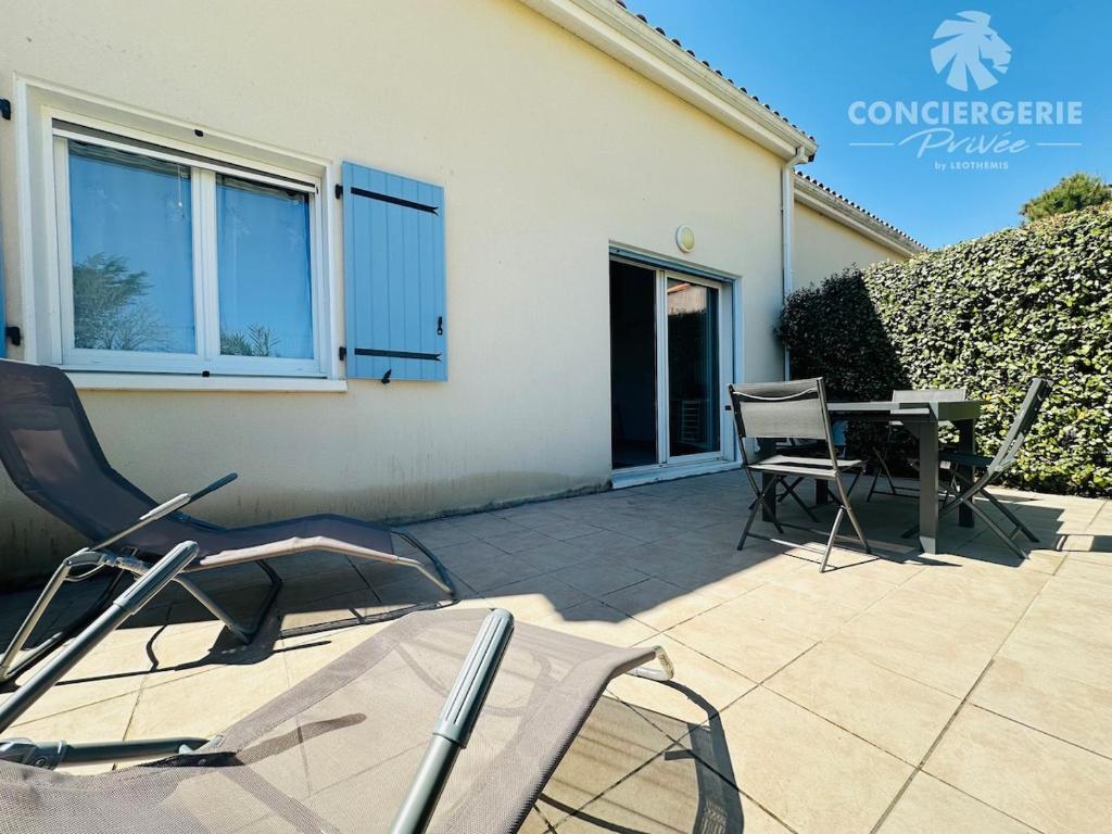 un patio avec des chaises et une table devant une maison dans l'établissement Maison de vacances à 50m de la plage, à Marennes